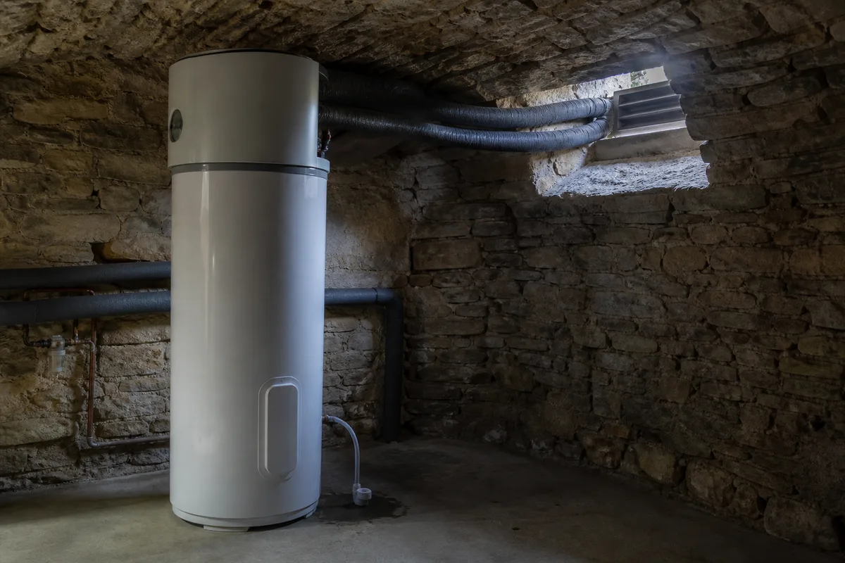 Chauffe-eau thermodynamique et ses gaines dans un sous-sol voûté de maison en pierre